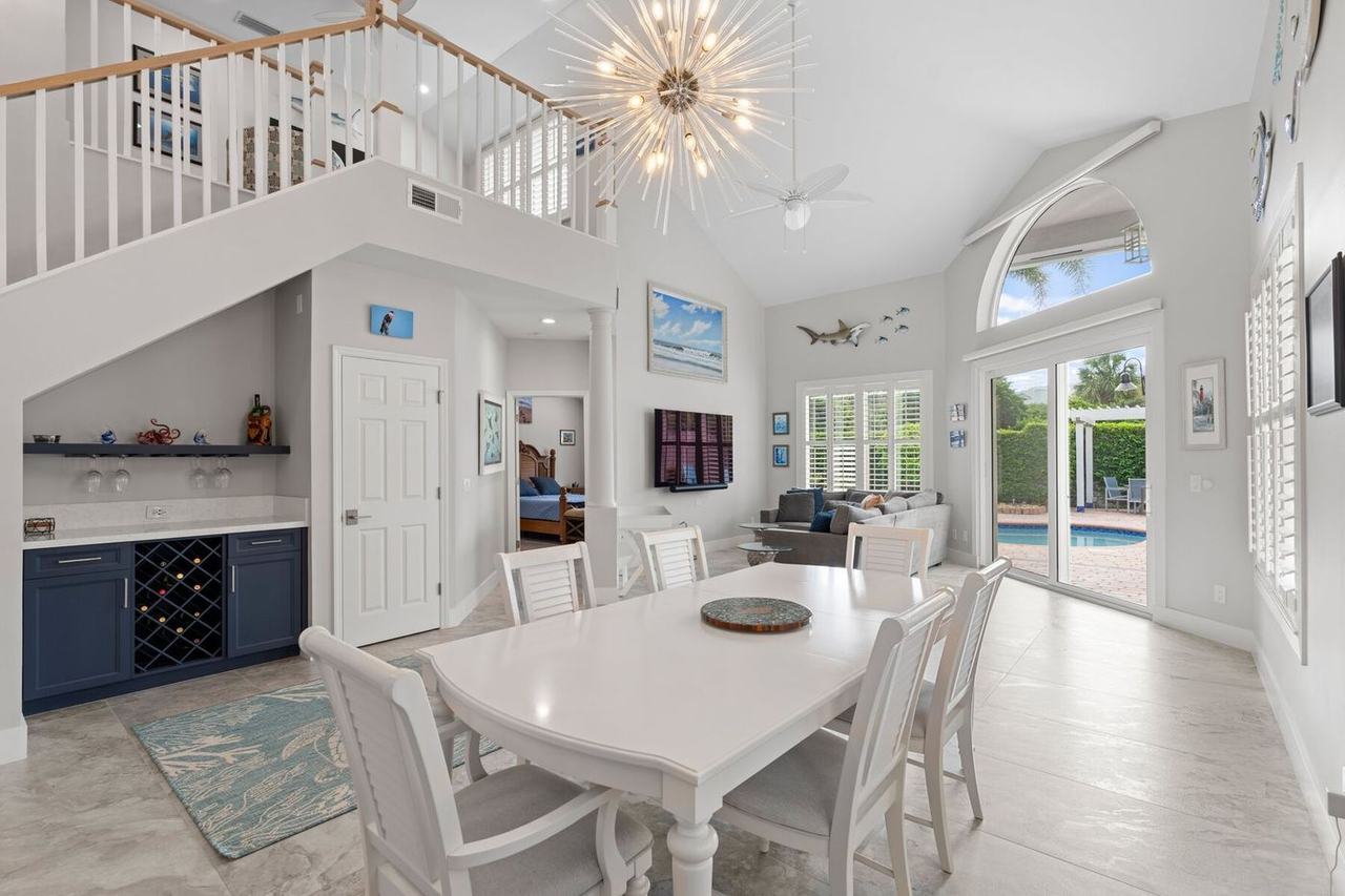 Vaulted living and dining room with a starburst chandelier, wine bar and sliders to the pool