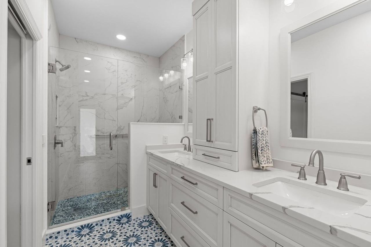 Renovated primary bath with walk-in shower, pebble mosaic floor and dual vanity
